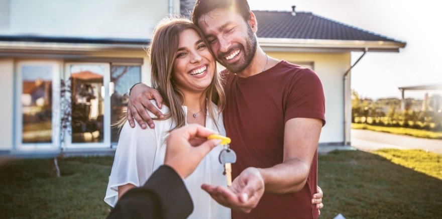 Immobilien – Lachendes Paar bekommt Schlüssel zu neuem Eigenheim