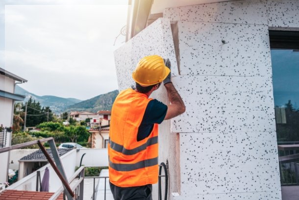 Energetische Sanierung – Bauarbeiter dämmt die Außenwand eines Hauses