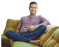 Mann sitzt mit Tasse in der Hand auf Sofa